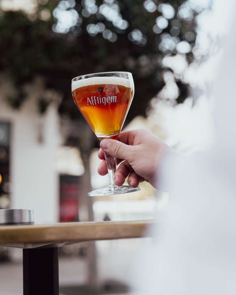 Verre d'Affligem Blonde levé en terrasse