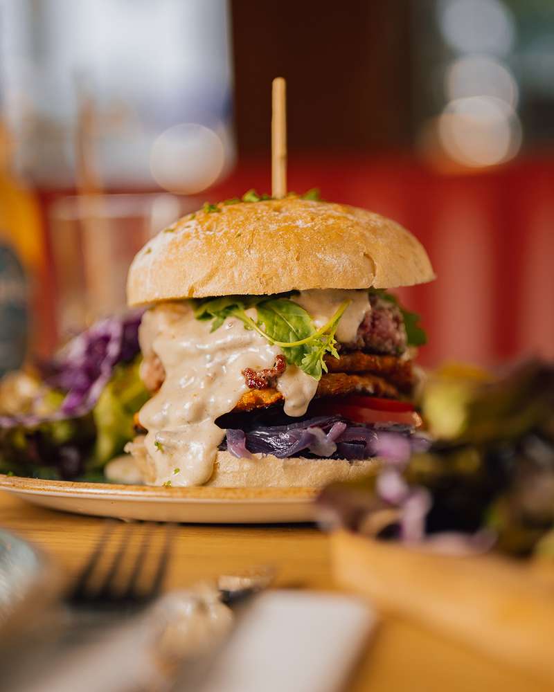 Burger, sauce, salade et chou rouge, servi sur une planche