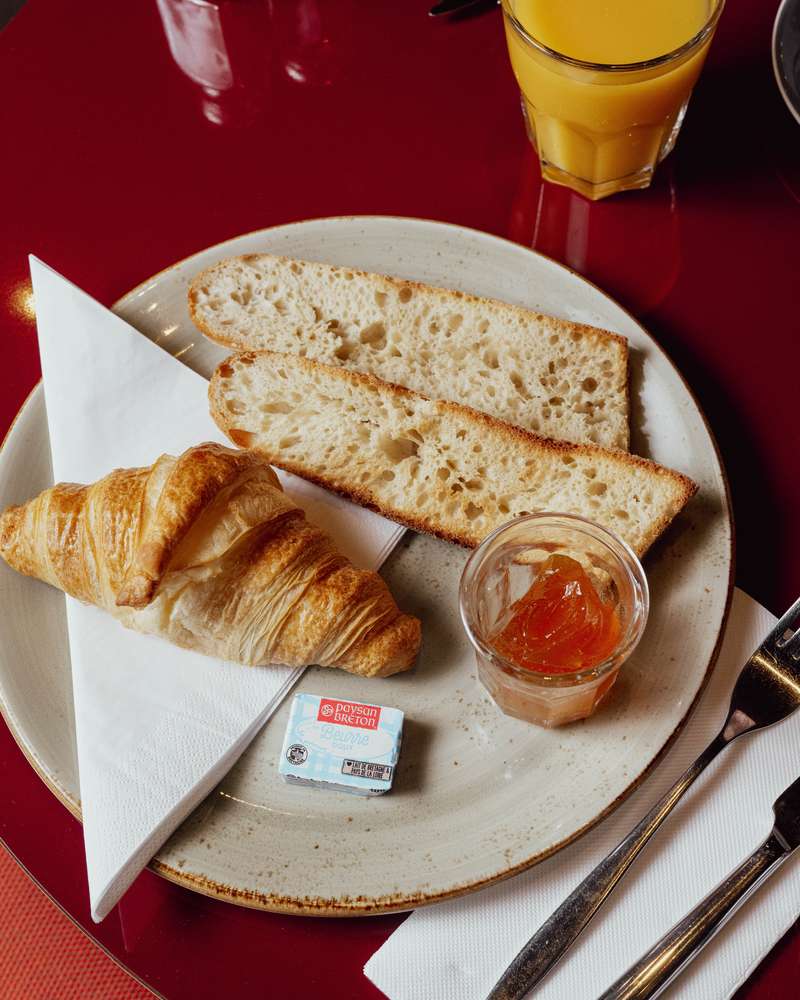 Croissant, tartines, confiture et jus d'orange pour le petit-déjeuner