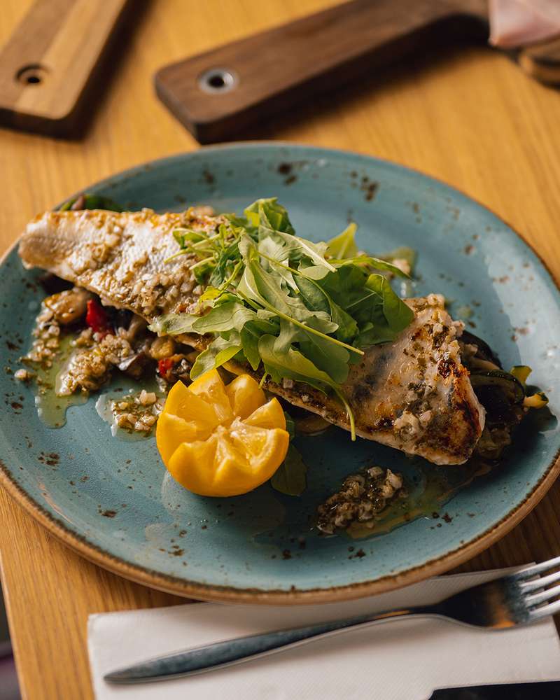 Filet de poisson grillé, roquette et citron sur une assiette bleue