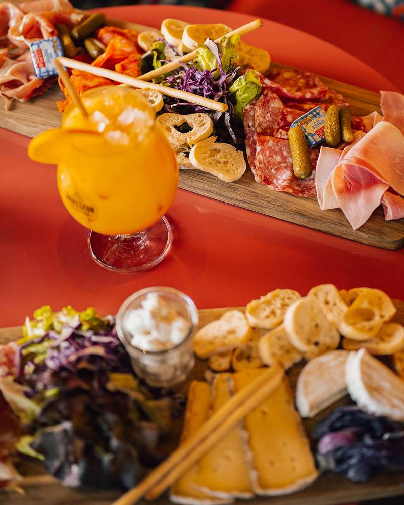 Planches de charcuterie et de fromages à partager, avec un cocktail orange