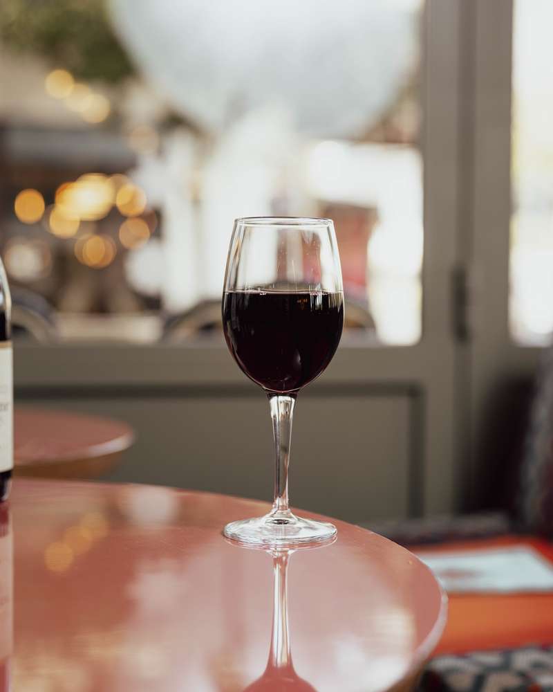 Verre de vin rouge sur une table, devant les grandes baies vitrées